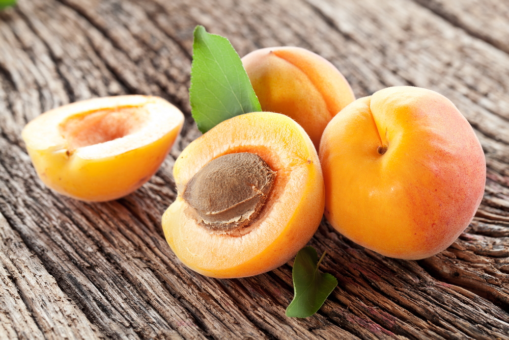 Apricots with leaves on the old wooden table.